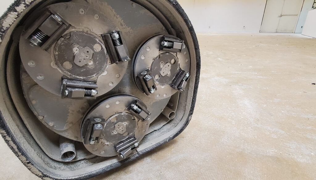 Carbide scrapers for carpet glue removal on a concrete floor grinder.